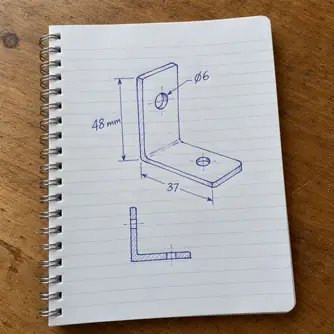Sketsa tangan braket L dengan ukuran dalam milimeter di buku catatan